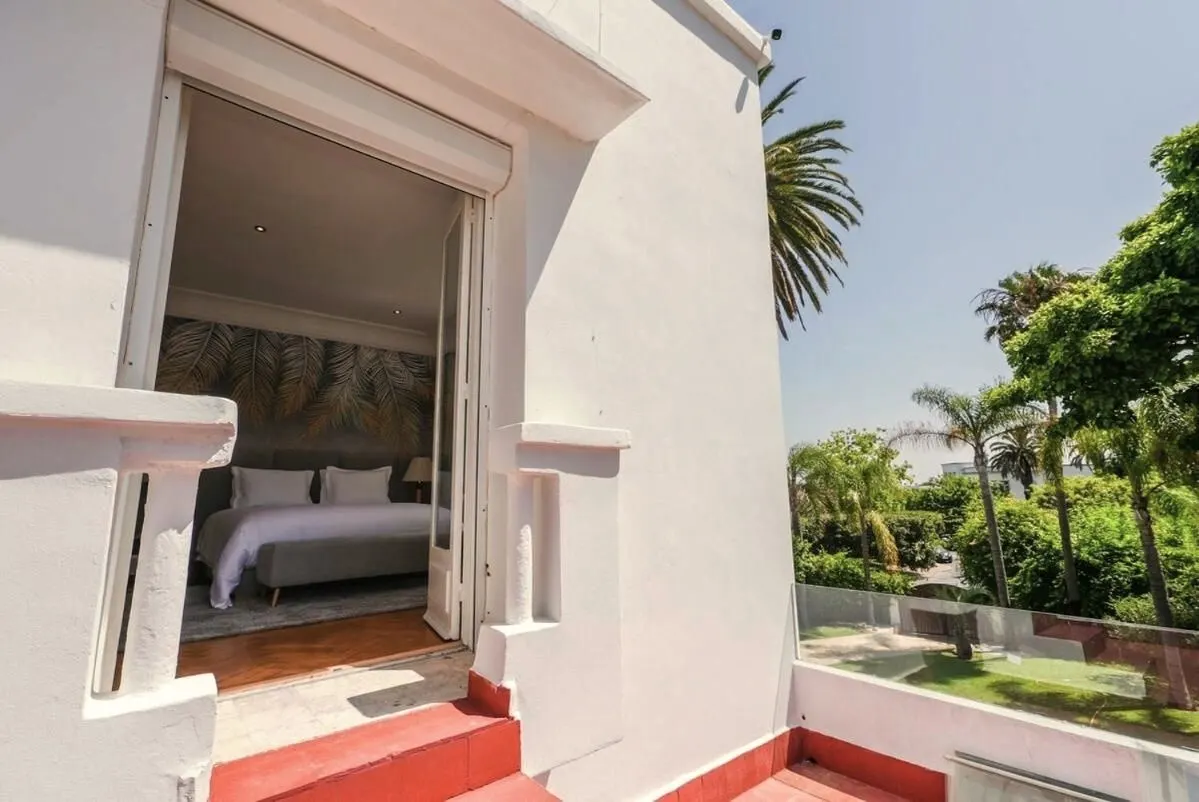 From an upstairs balcony: white balustrade, palms and the garden.