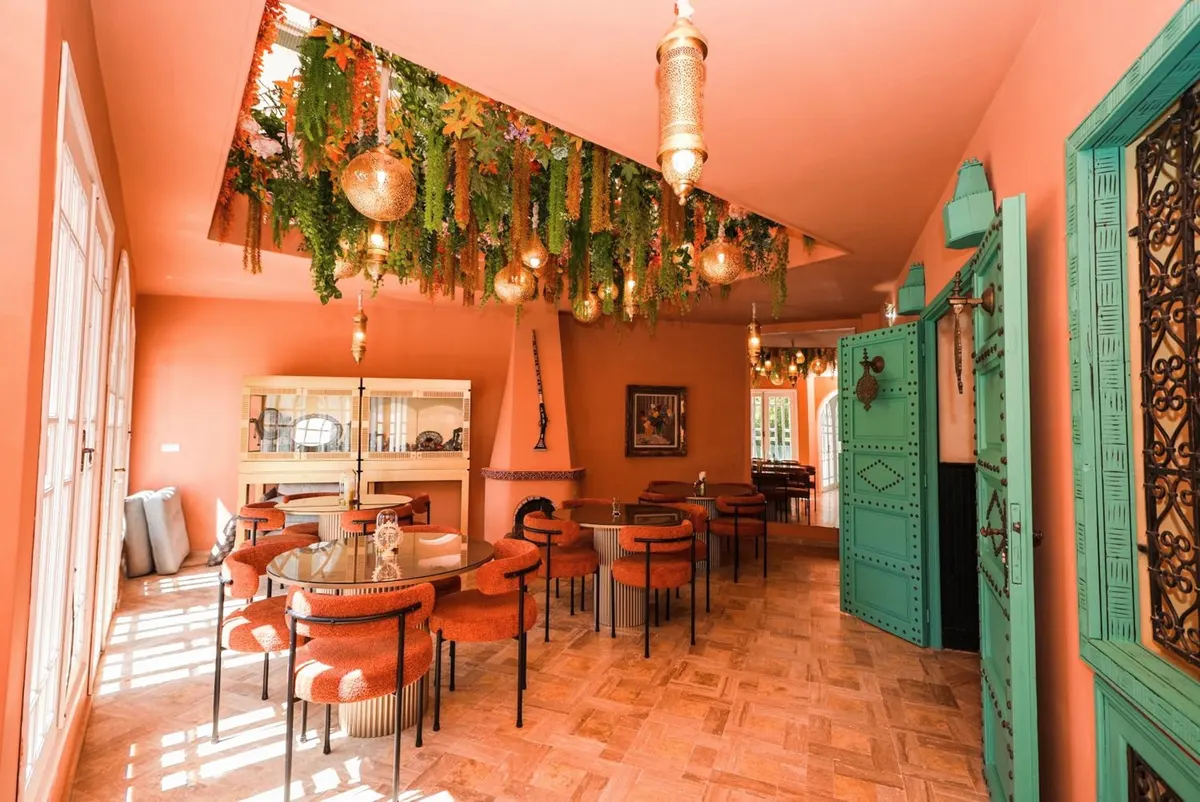 The coral room: coral walls, a canopy of greenery, lanterns, velvet chairs and carved emerald doors.