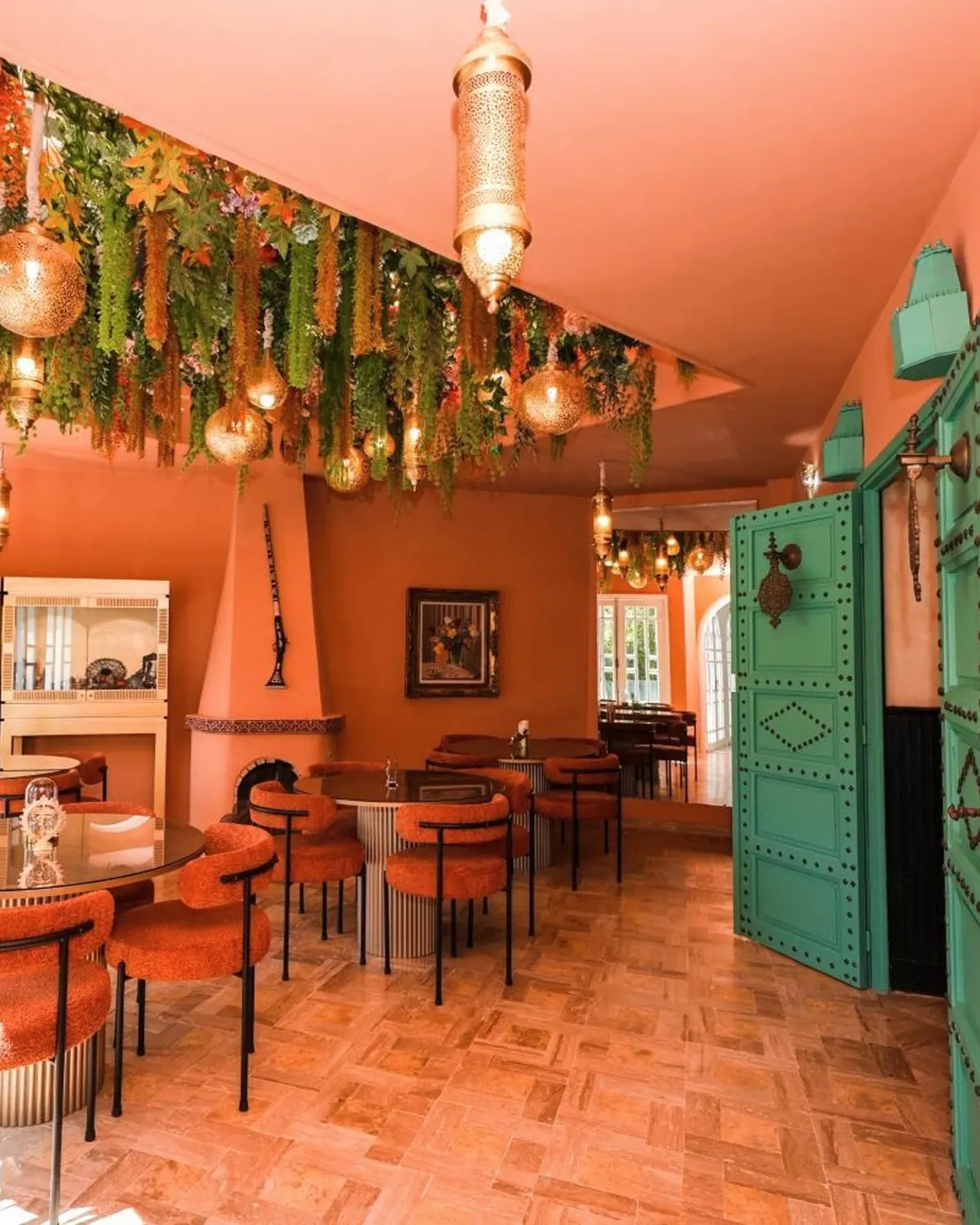The coral room: coral walls, a canopy of greenery, lanterns, velvet chairs and carved emerald doors.