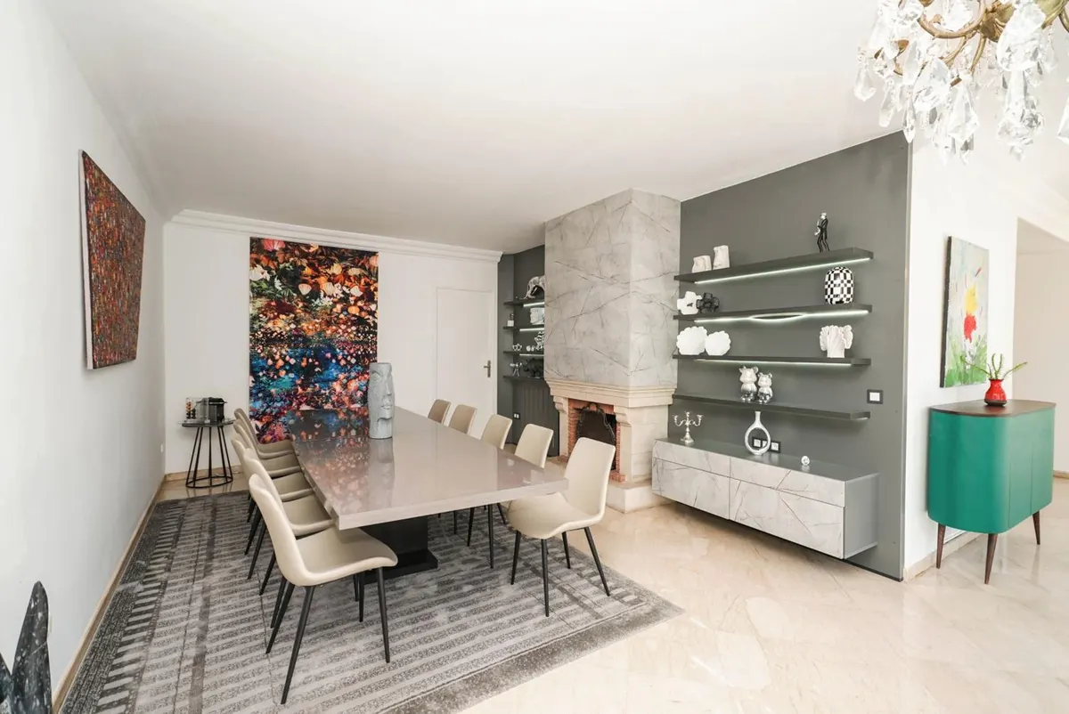The dining room: a long table, a marble fireplace and an abstract canvas.