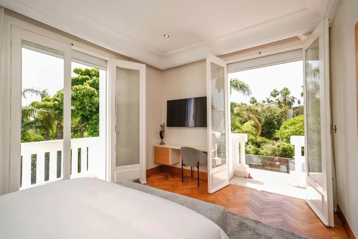 A bedroom with its French windows open onto the garden palms.