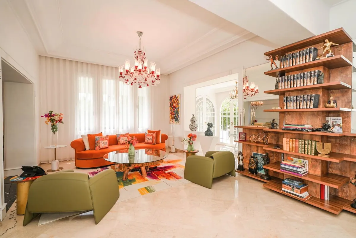 The library: wooden shelves, orange and olive velvet sofas.