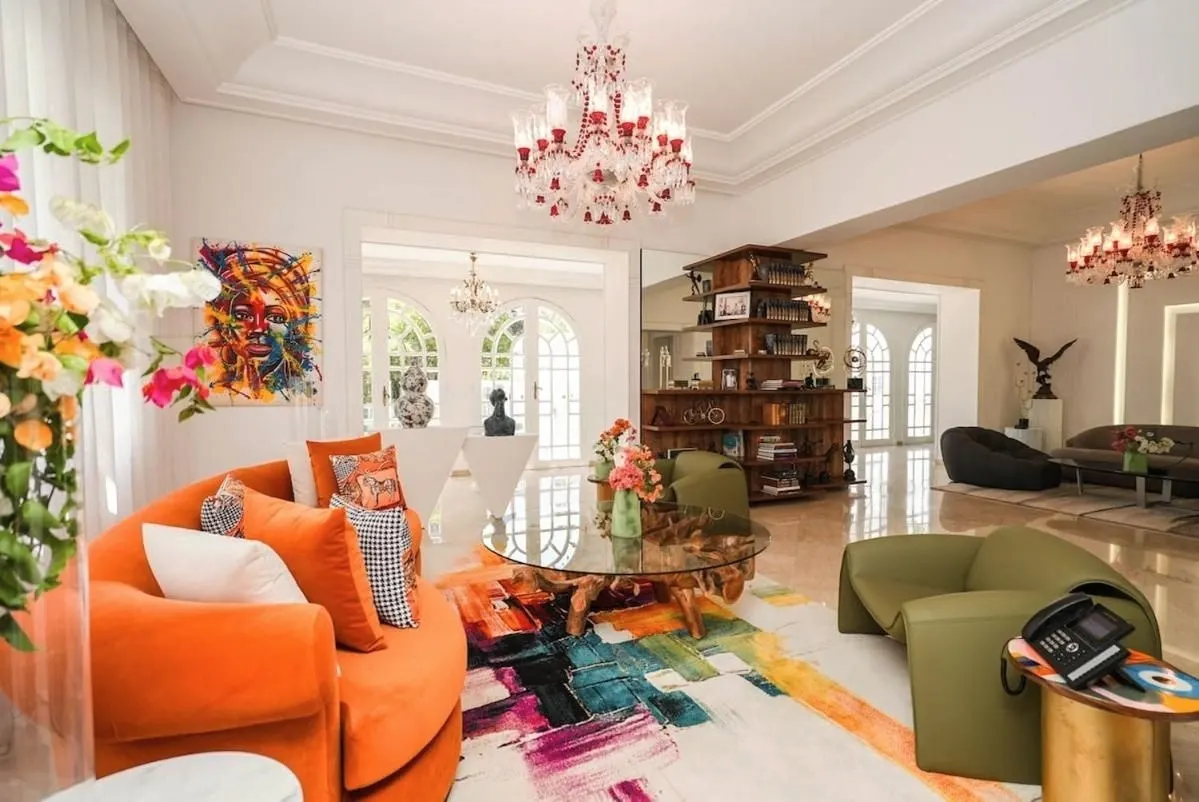 The library: orange sofa, flowers and a colourful rug.