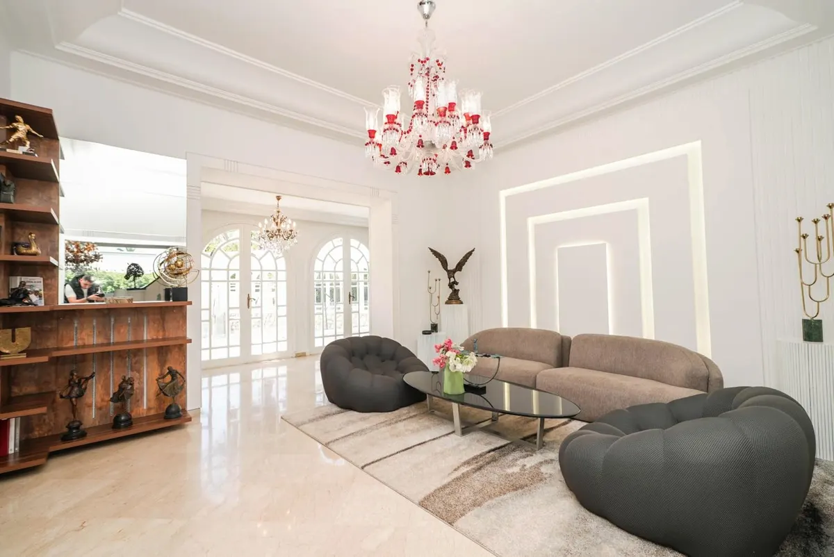 White salon with bouclé armchairs and a stepped plaster niche.