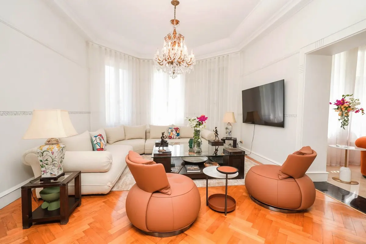 The white salon: cognac leather chairs, an ivory sofa and a crystal chandelier.