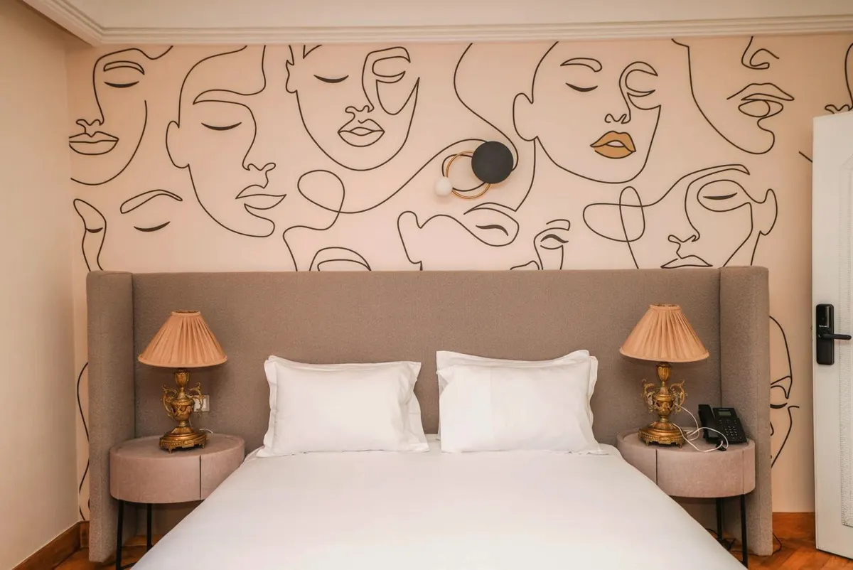 Deluxe Double Room: the bed and the mural, with brass lamps.
