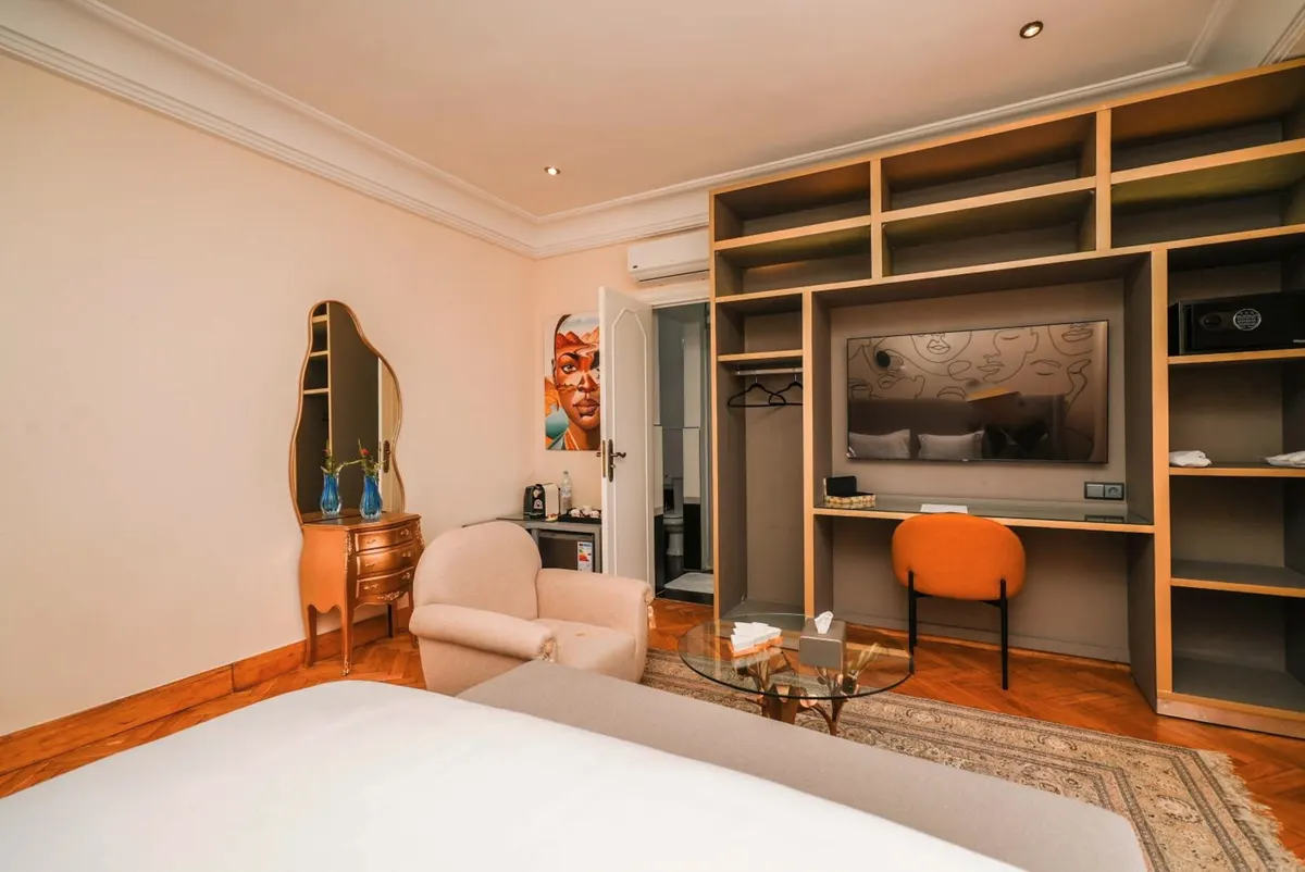 Deluxe Double Room: sitting corner and grey-and-brass shelving desk.