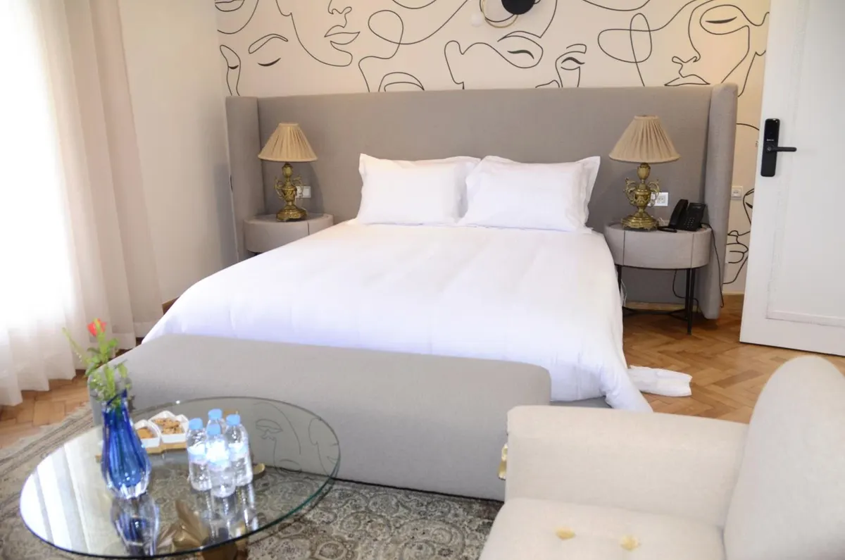 Deluxe Double Room: bed and glass table with flowers.