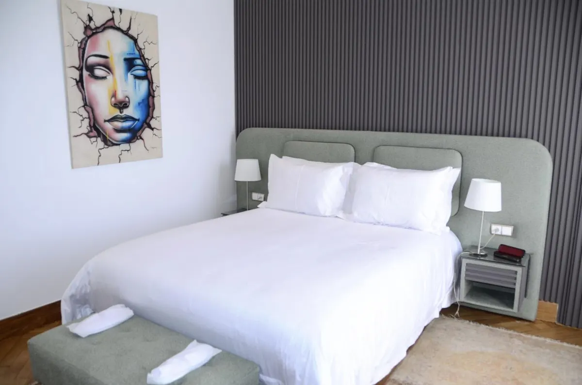 Double Room: white bed under a pop-art portrait.