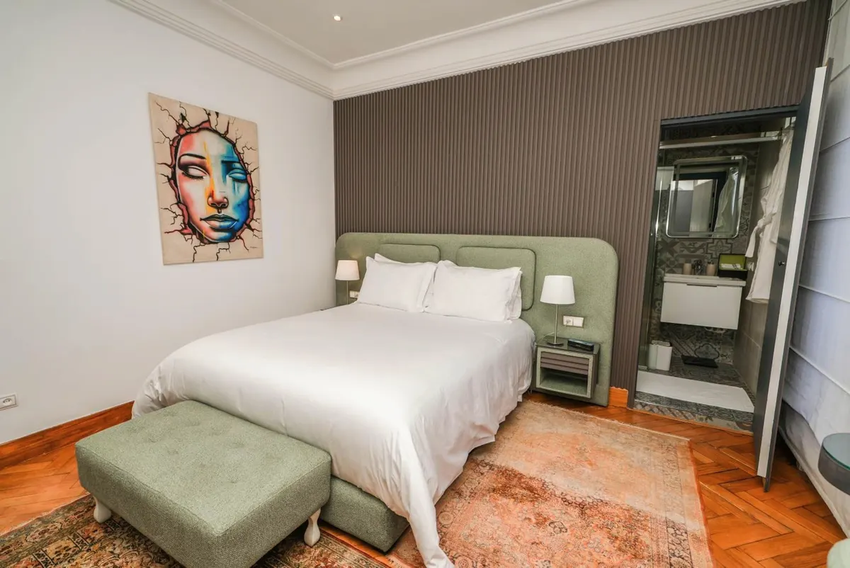 Double Room: sage bed and ottoman, pop-art portrait, grey fluted wall.