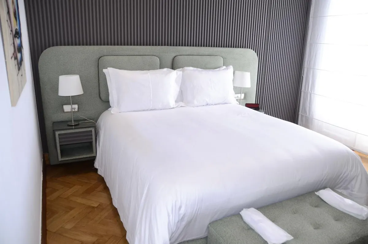 Double Room: white bed, grey upholstered headboard and sage bench.