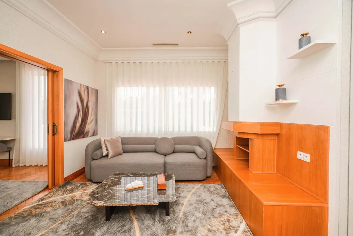Family Studio: living room with a grey sofa, marble coffee table and warm-wood built-ins.