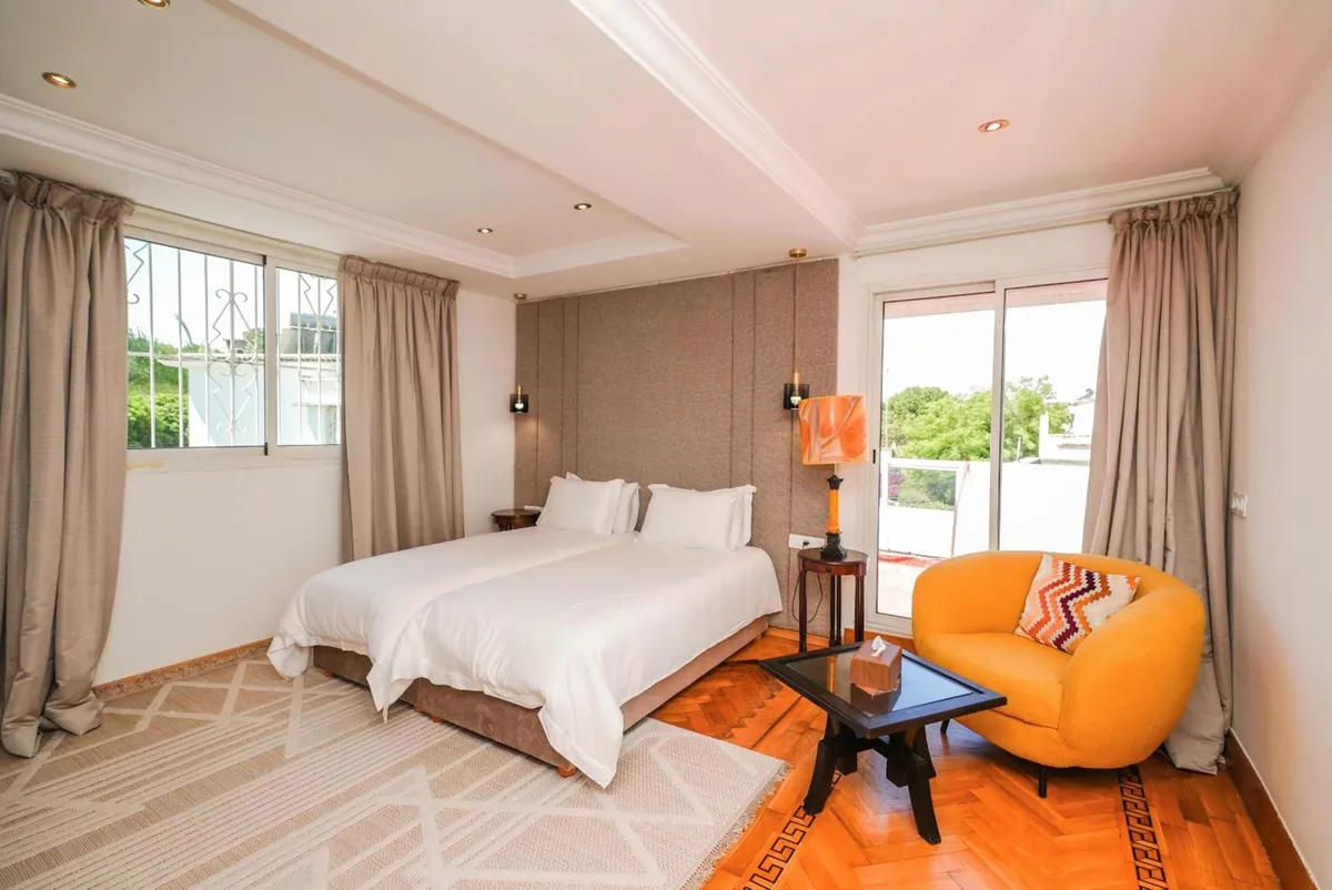 Family Studio: second bedroom with an orange armchair and two windows.