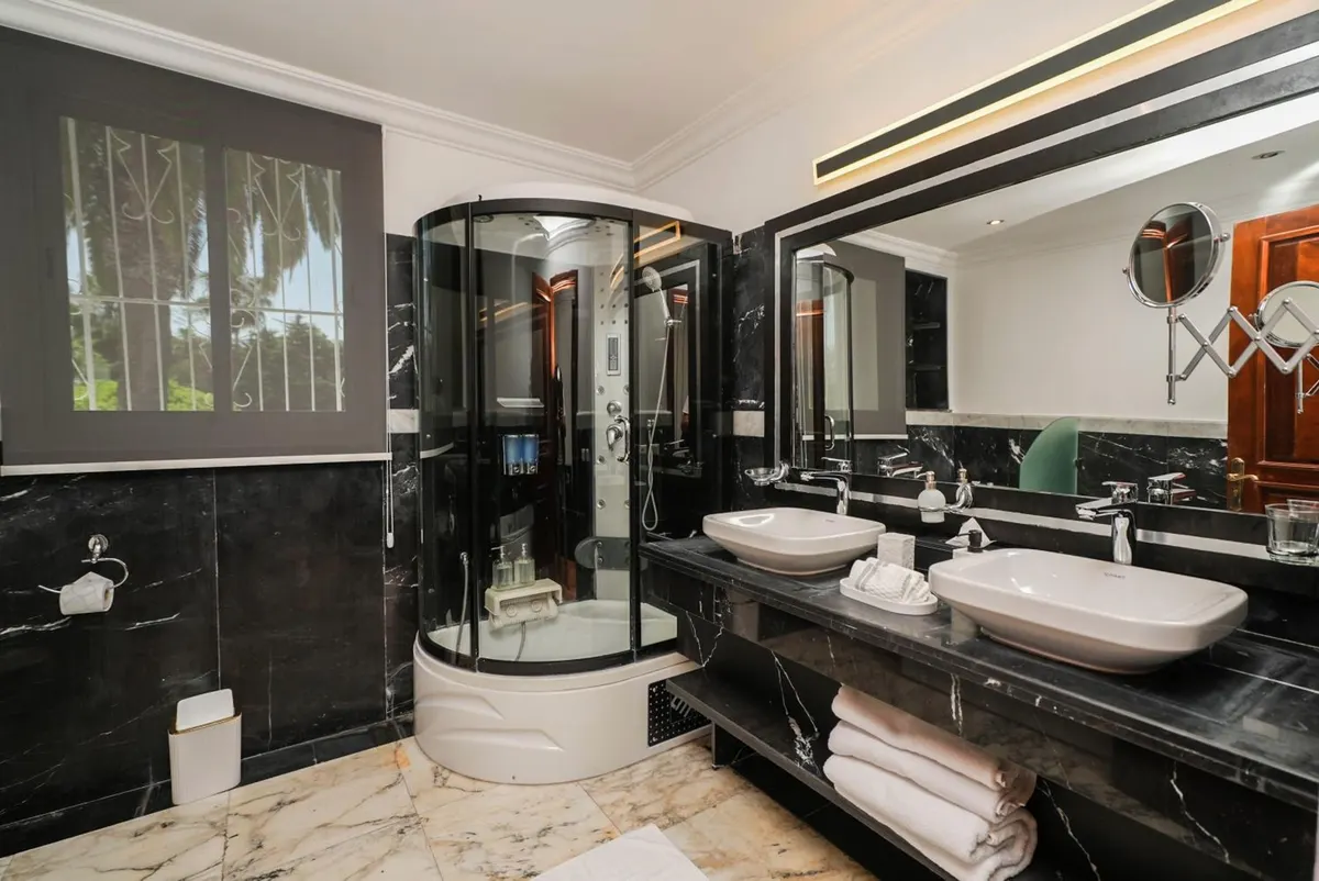 Family Studio: black marble bathroom with twin basins and a round shower.